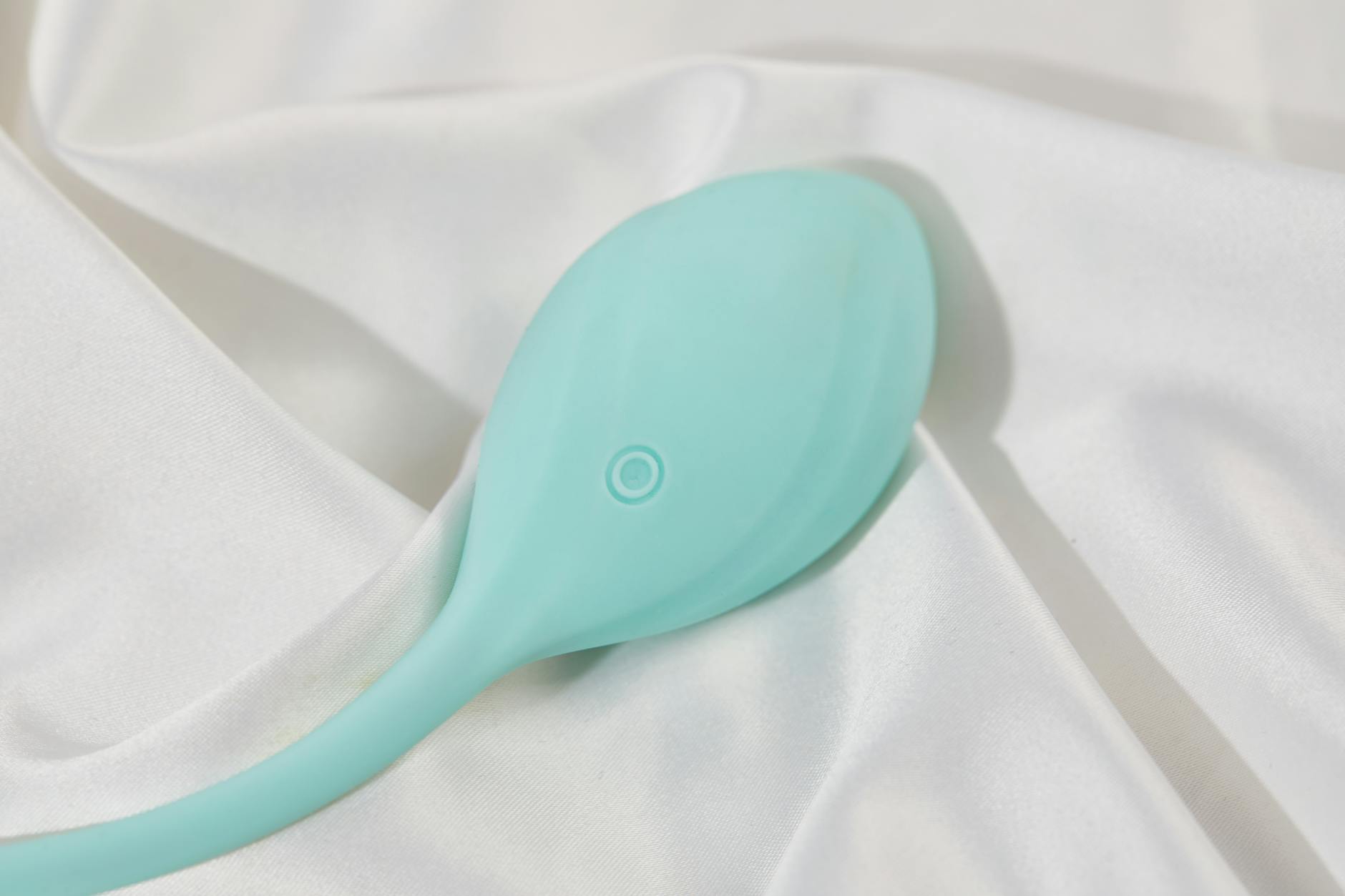 Hand, die einen Lemon-Vibrator auf weißem Seidengewebe zeigt, elegant arrangiert