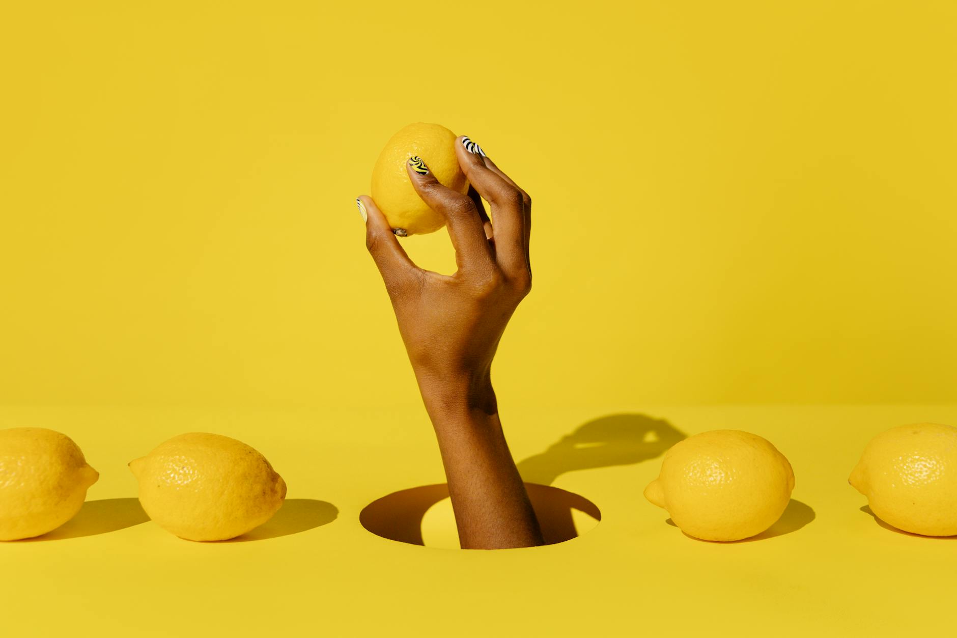 Hand holding a lemon on yellow background, symbolizing fresh approach to clitoral suction toys