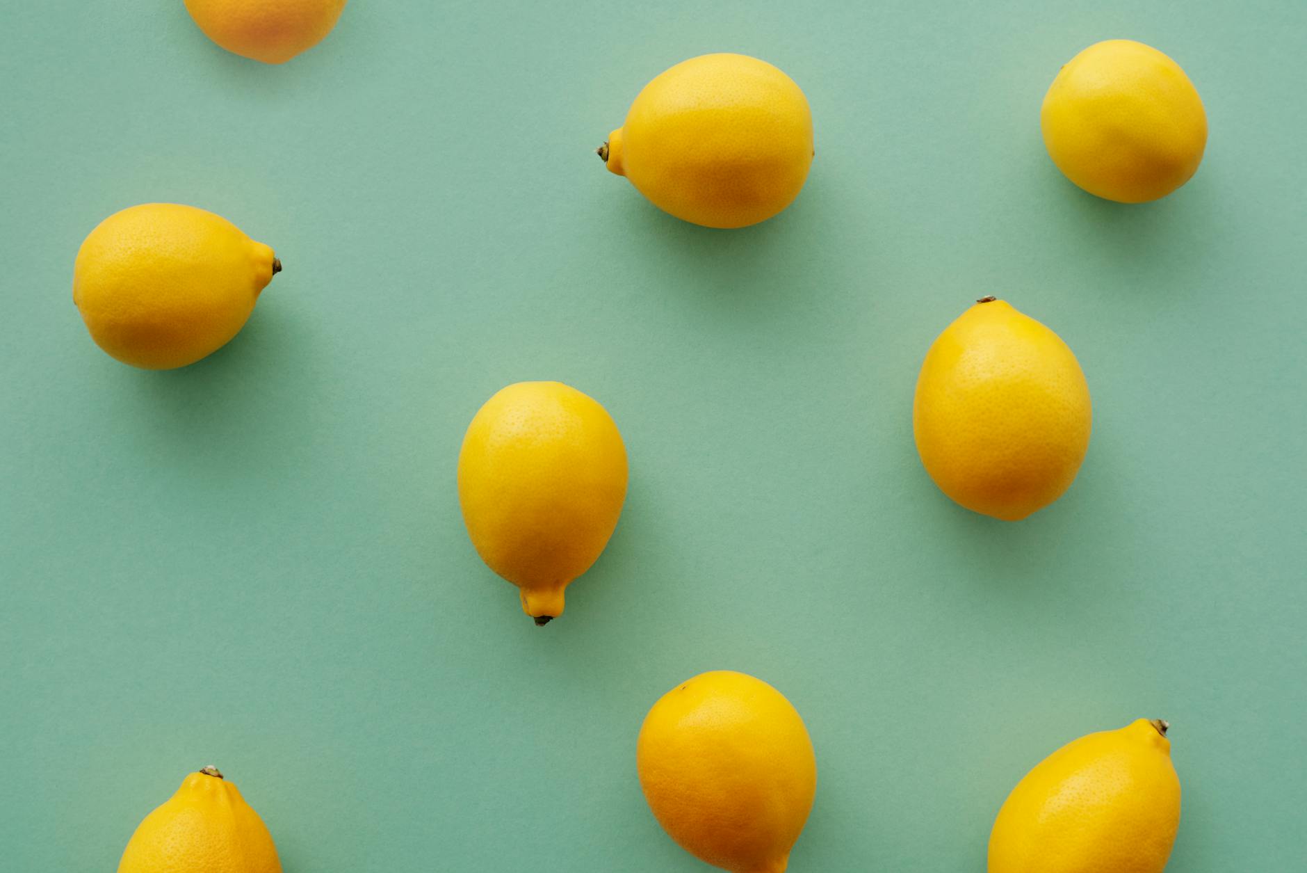 Bright yellow lemons on a pastel green background, representing freshness and natural pleasure