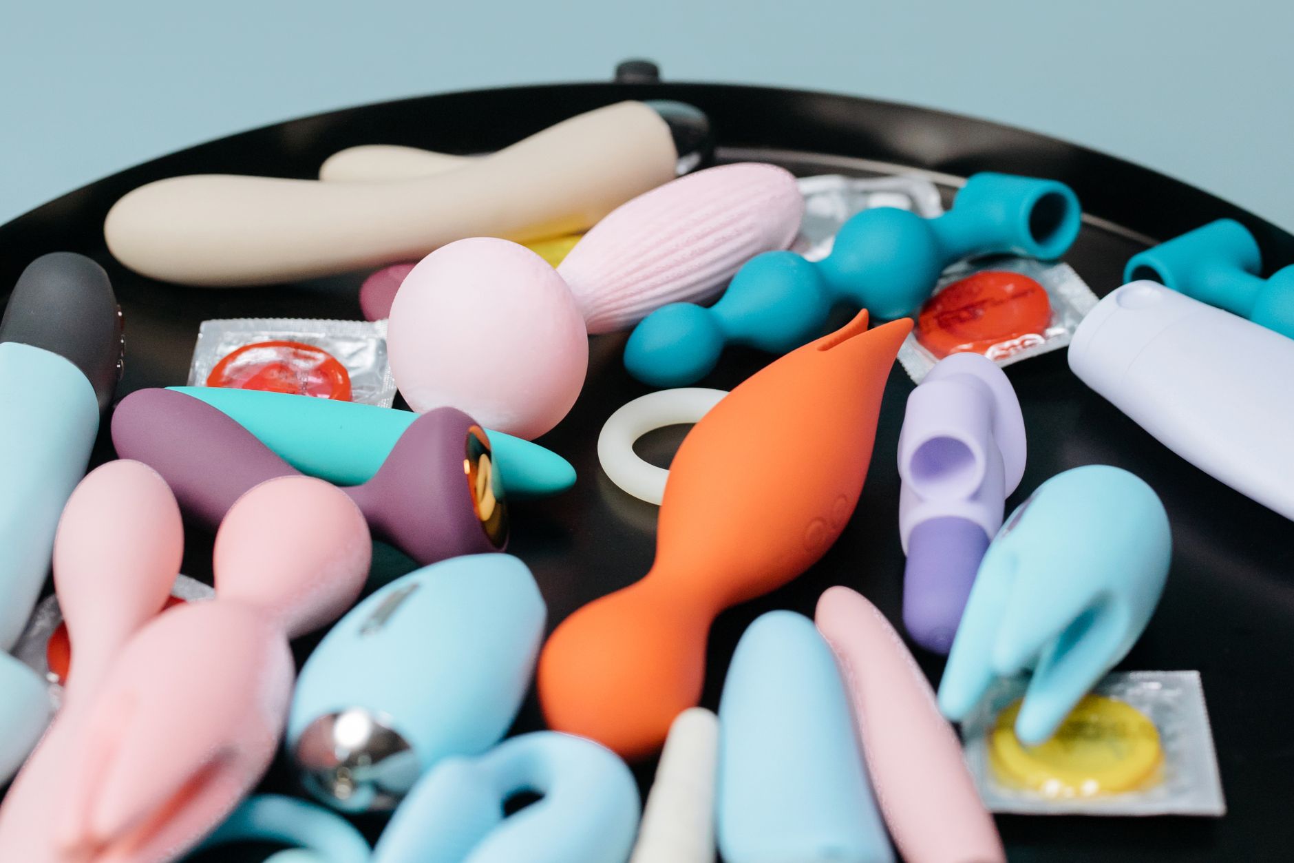 A collection of colorful vibrators displayed on a tray, including lemon clitoral vibrators and other pleasure toys