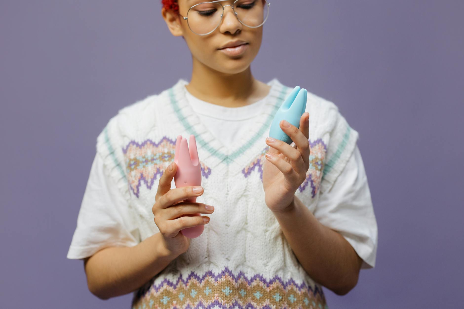 Woman holding a blue and pink clitoral vibrator with a thoughtful expression while considering pleasure recovery
